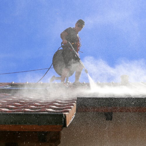 A man is cleaning the roof of a house
