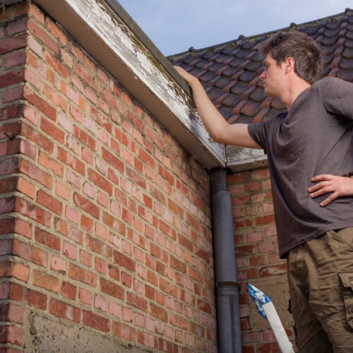 A man standing next to a brick wall.