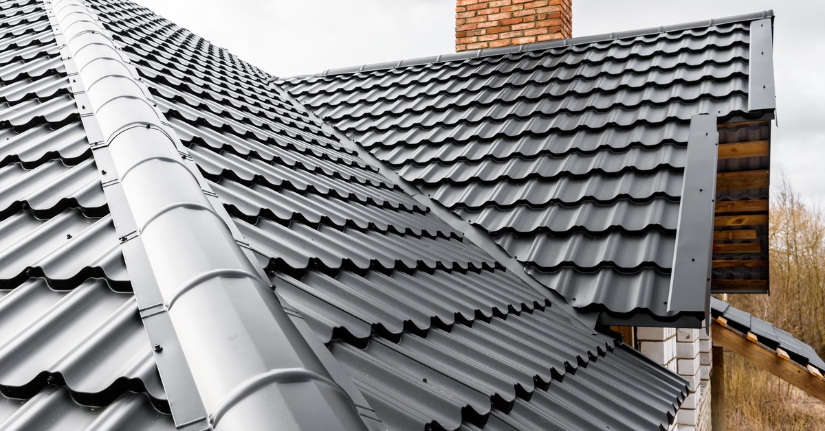 A Mediterranean-style roof in a dark black metal material. The home appears newly built with a brick chimney.