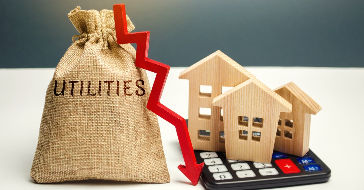 A small canvas bag with the word utilities. Next to it is a calculator with small wooden homes on top and an arrow pointing down.